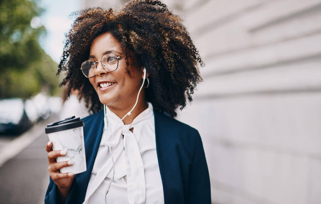 Women holding a coffee listening to music | Spotify’s North Star Metric