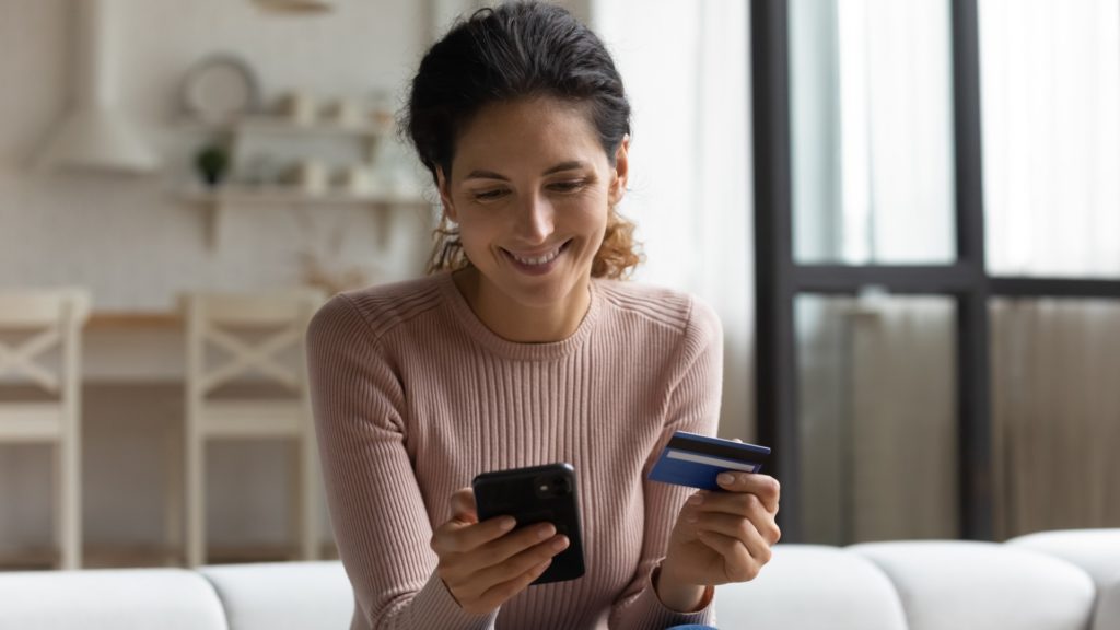 Smiling Woman Looking at Phone and Holding Credit Card | How Is a Growth Loop More Powerful Than a Funnel? | Teknicks