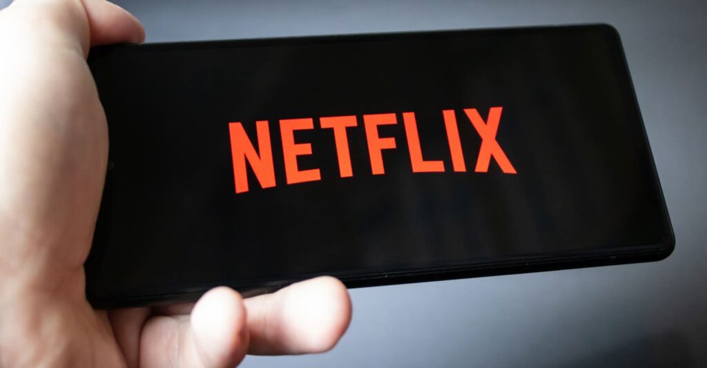 A hand holding a phone | Netflix’s North Star metric
