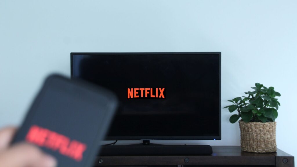 Person holds remote to TV as Netflix logo launches on screen | Embedding Network Effects