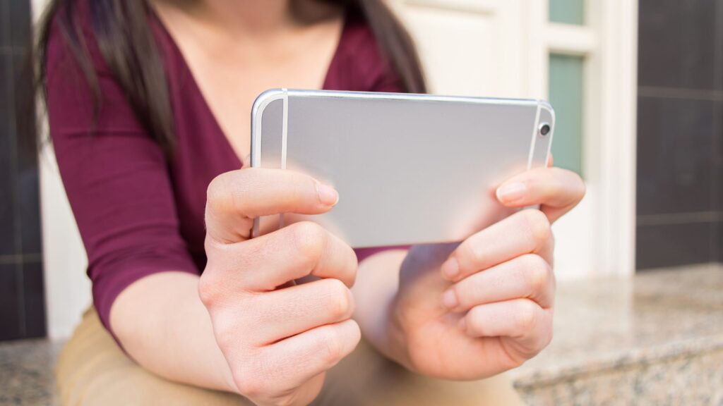 Back of silver iPhone shows as woman holds it horizontally with both hands | Embedding Network Effects