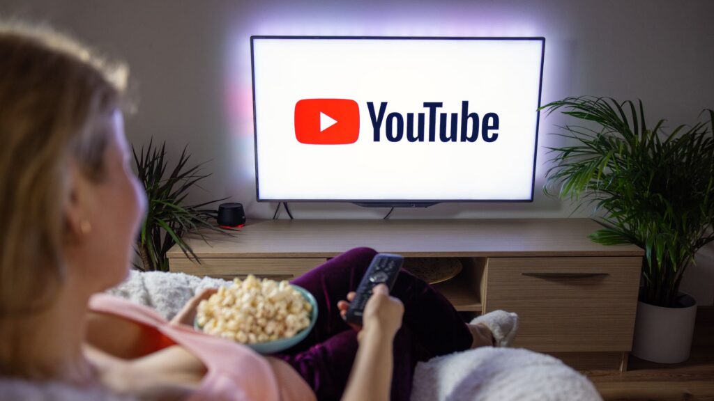 Person holds remote and bowl of popcorn while launching Youtube on TV | Embedding Network Effects