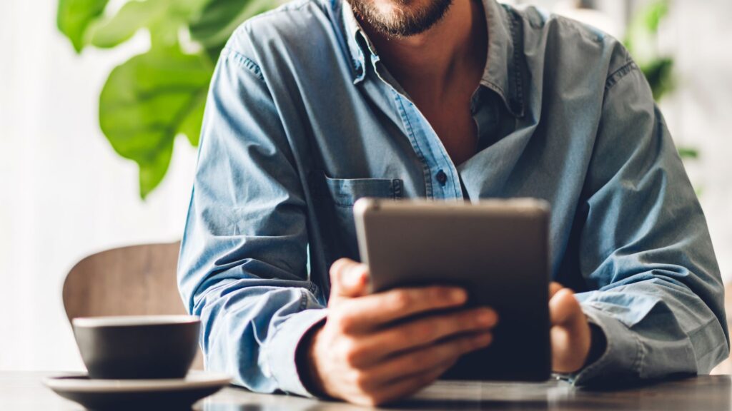 Close up of SaaS manager holding silver tablet on office couch | Finding the Right SaaS Users