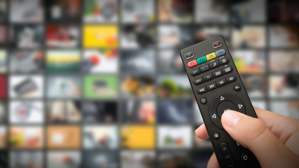 Close up of person holding TV remote over background of blurred streaming titles | Brand Network Effects