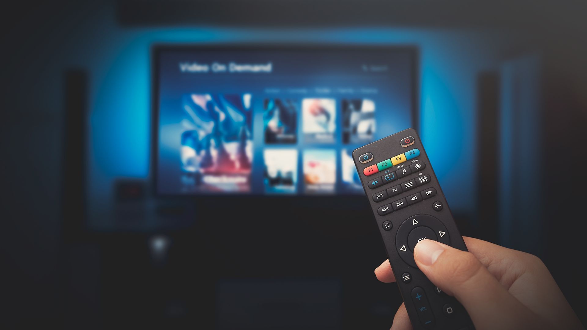 Person holding TV remote up to a blurred screen of movie titles | Monetization and Pricing Strategies
