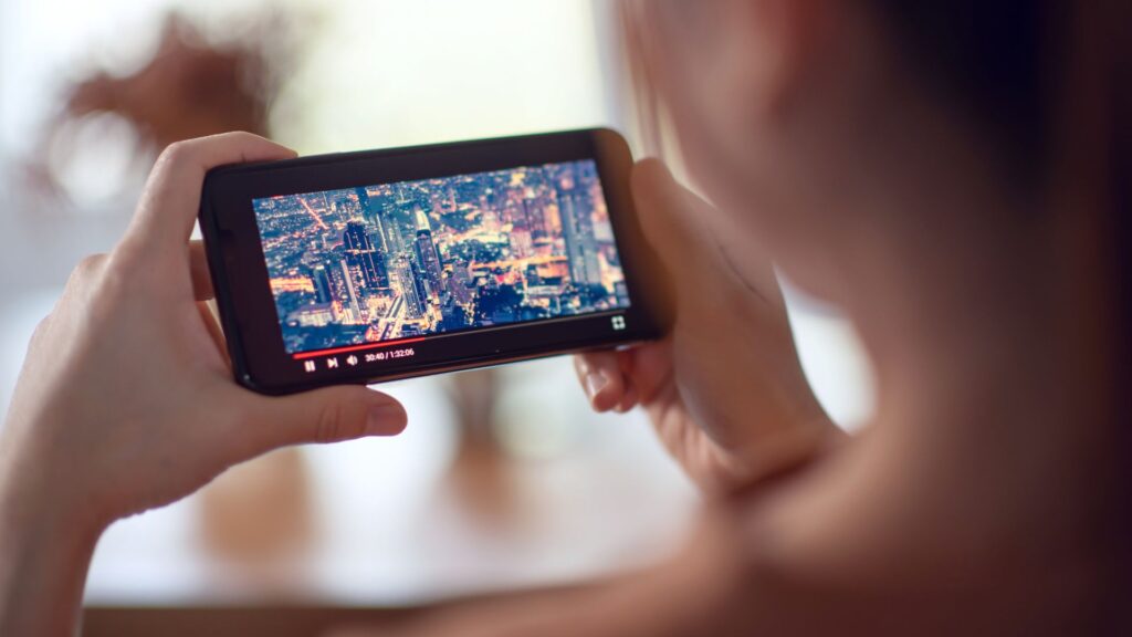 Close up of video displaying city skyline as person holds smartphone | User Activation for Streaming Companies