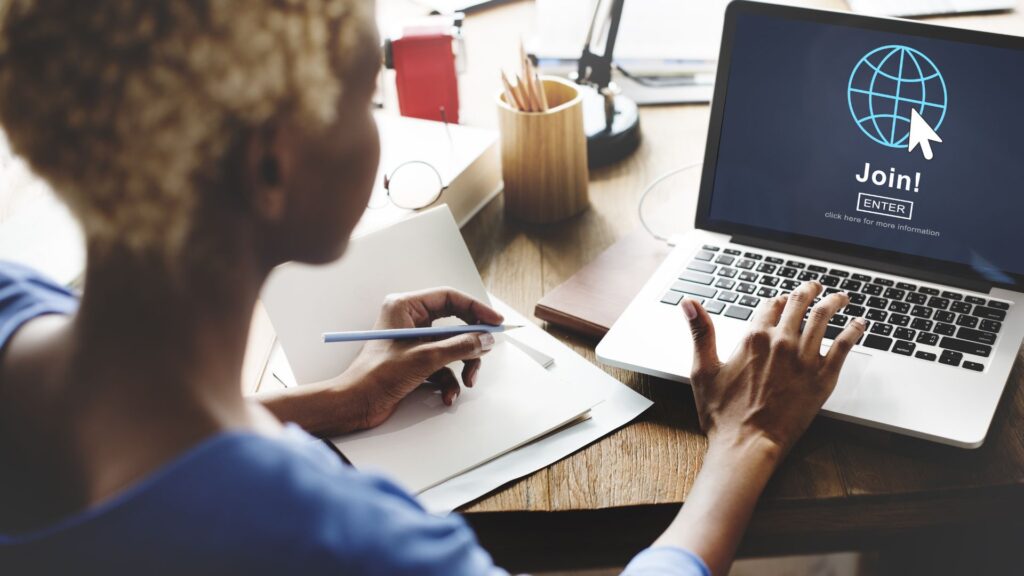 Woman sits at desk with papers while logging into laptop |Indirect Brand Network Effects for Streaming Companies