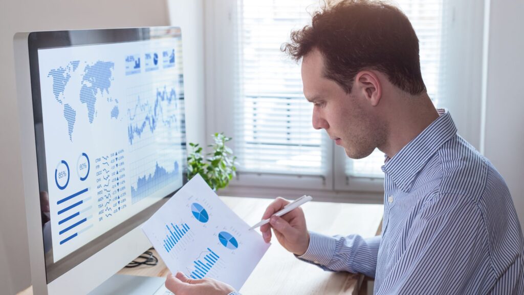 SaaS employee compares paper graph to map on desktop computer | Measuring Network Effects