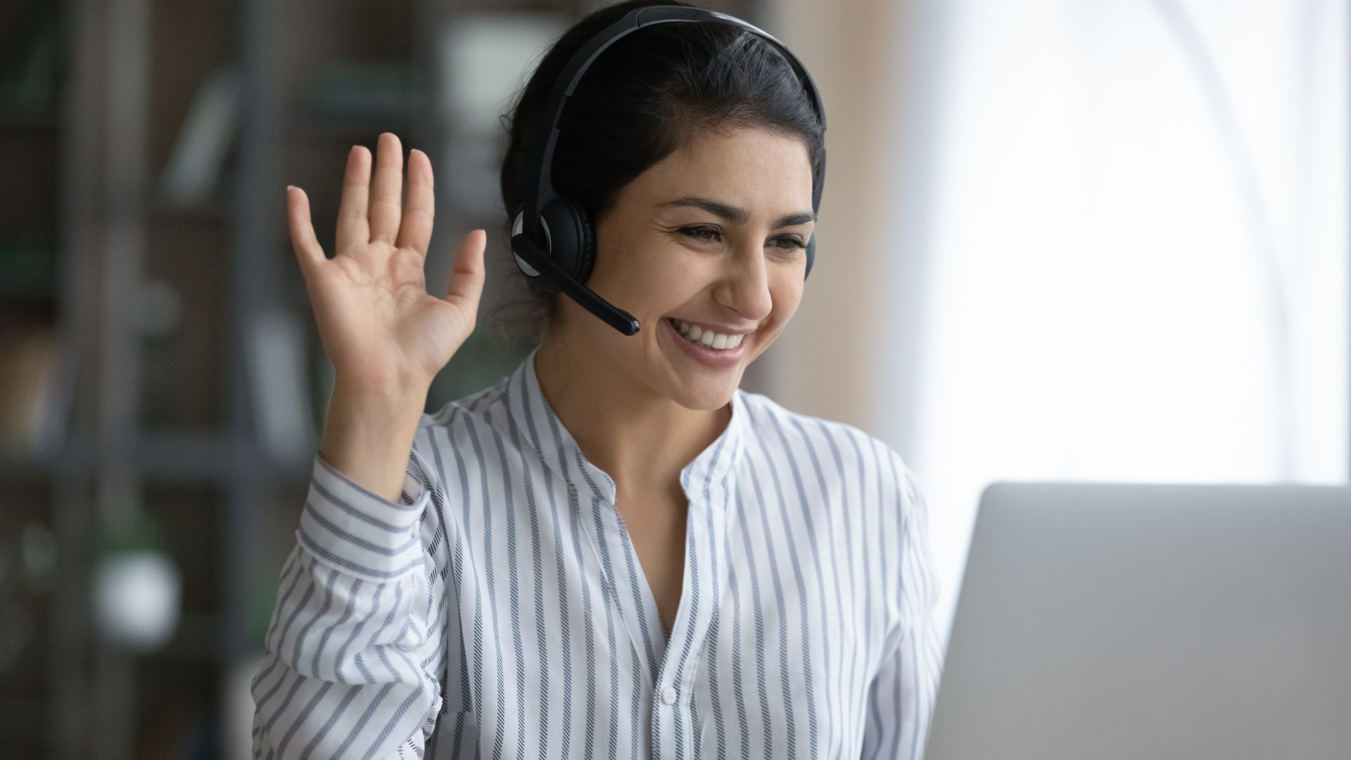 Manager smiles and raises hand while talking on headset | Monetization and Pricing Strategies