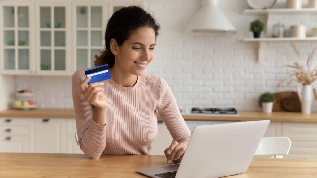 SaaS user smiling while using credit card to make purchase on laptop | Measuring Network Effects