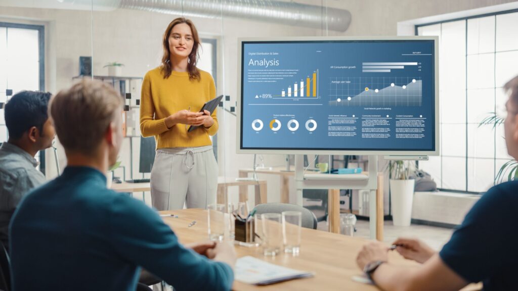 SaaS manager stands next to screen of analysis charts while presenting | Embedding Network Effects