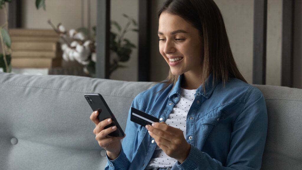 SaaS user smiles while using smartphone and credit card to upgrade her subscription plan | ARPPU