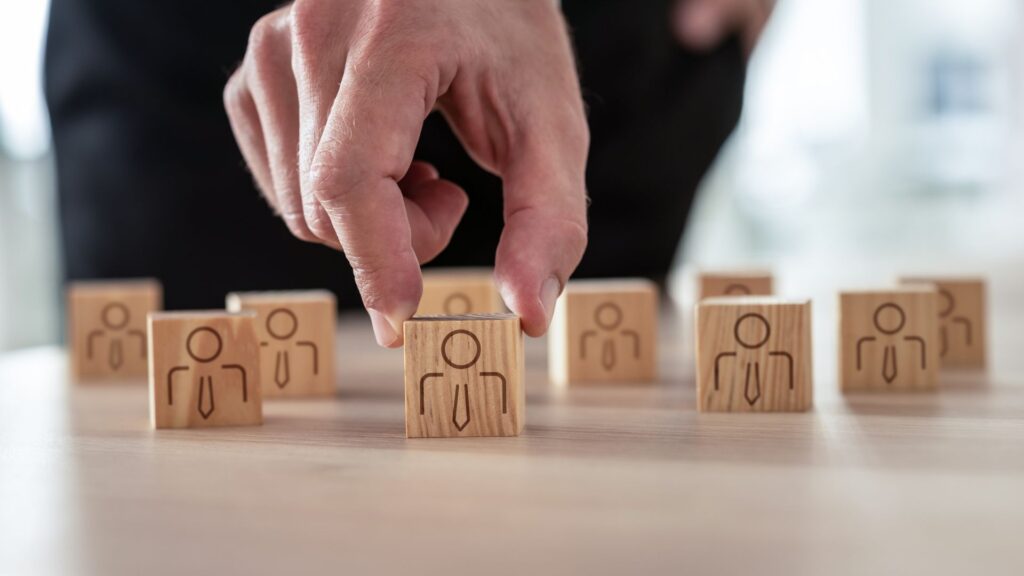 Close up of fingers picking up tiny wooden block marked with user icon | Finding the Right SaaS Users