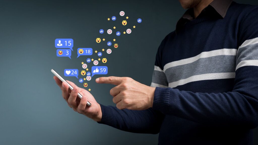 Social network notification icons hover over smartphone in man’s hand | Social Media and Brand Network Effects