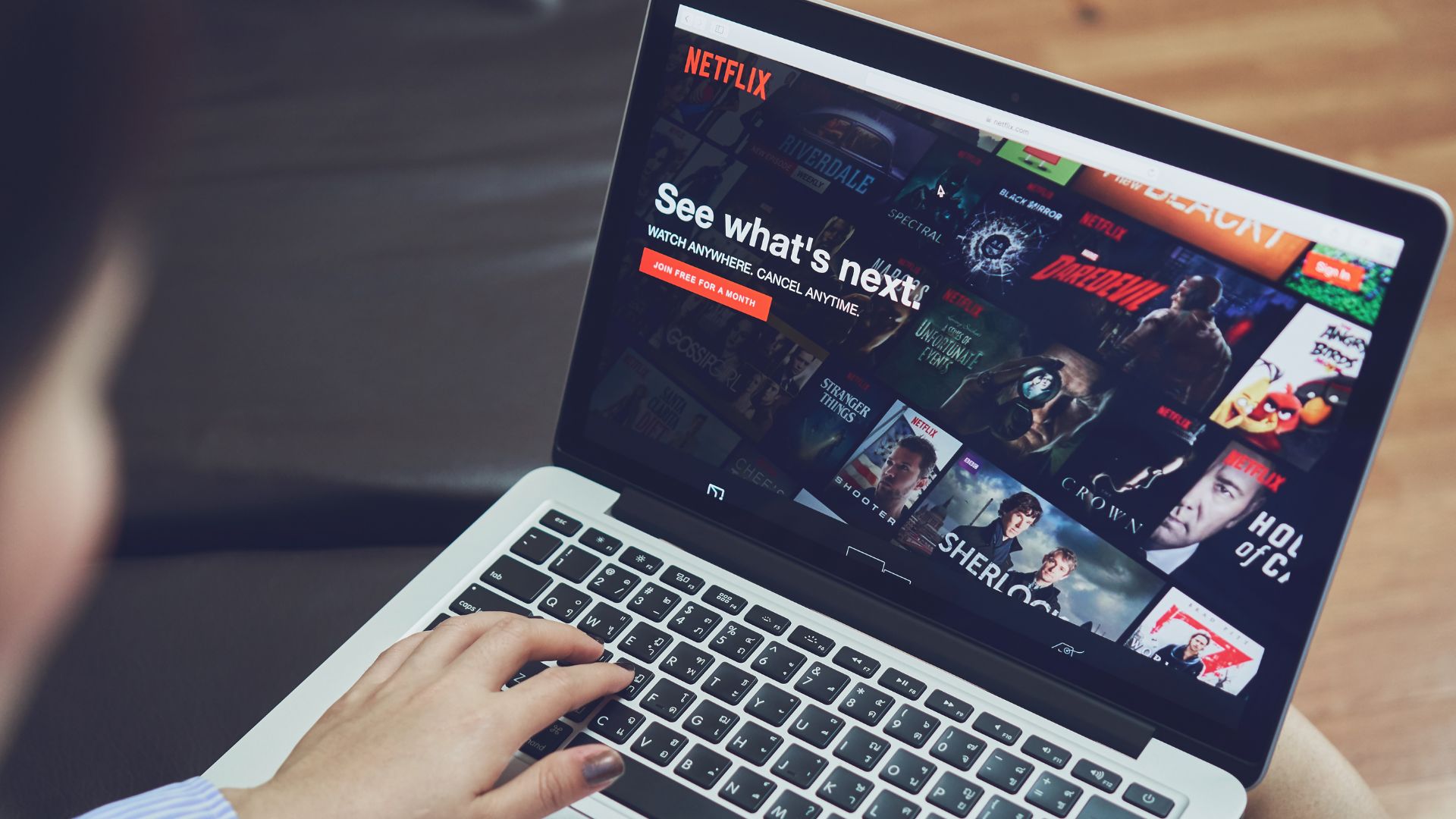 Person loading Netflix on their laptop while sitting on couch | Monetization and Pricing Strategies