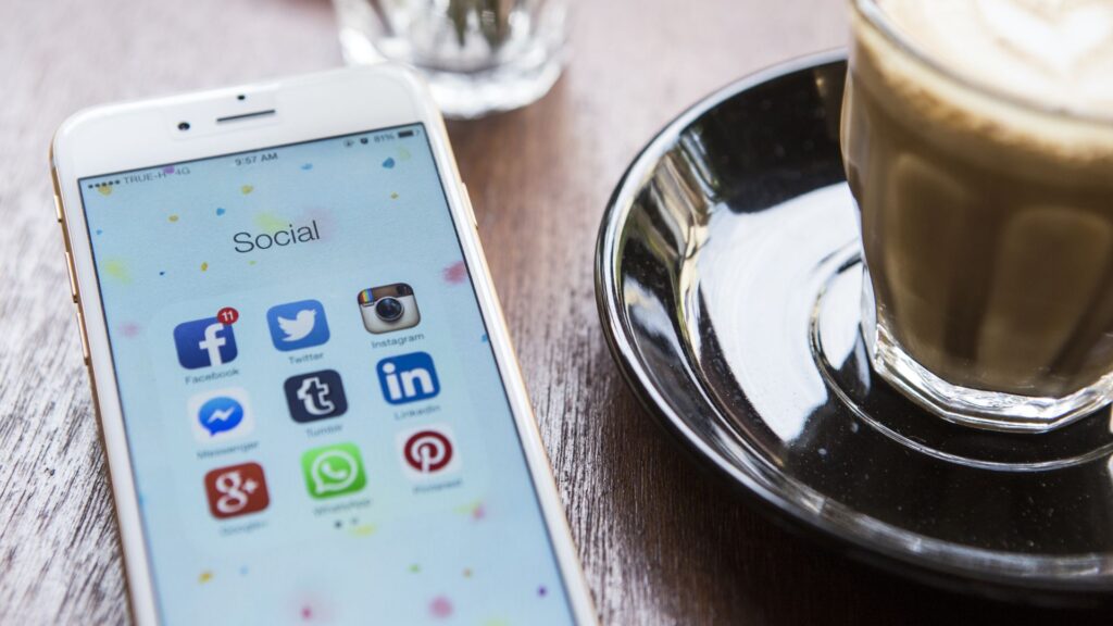 Smartphone displays social media apps while resting on table next to coffee | Measuring Network Effects